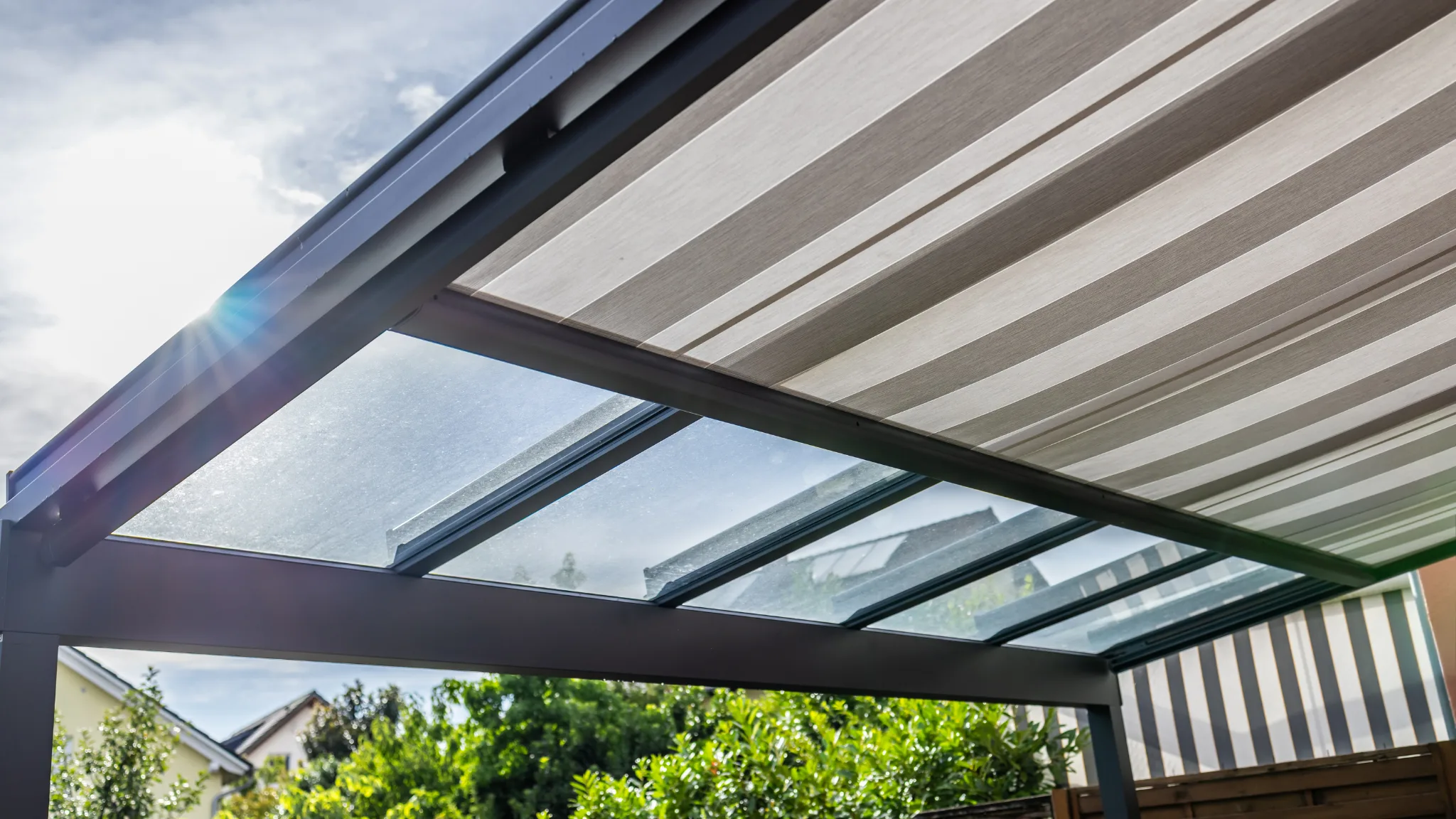 Markise mit Glasdach über einer modernen Terrasse — außenliegender Sonnenschutz